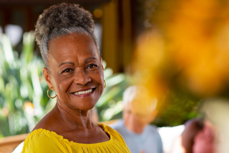 Mulher negra madura sorrindo confiante após tratamento All-on-4 ou protocolo tradicional na Clínica R7 Implantes no Catete, RJ.