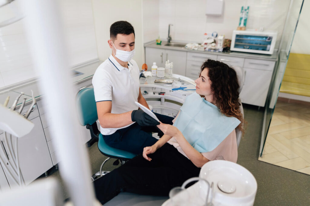 Dentista orienta paciente na cadeira odontológica sobre o pós-operatório da cirurgia zigomática na Clínica R7 Implantes, no Catete RJ.